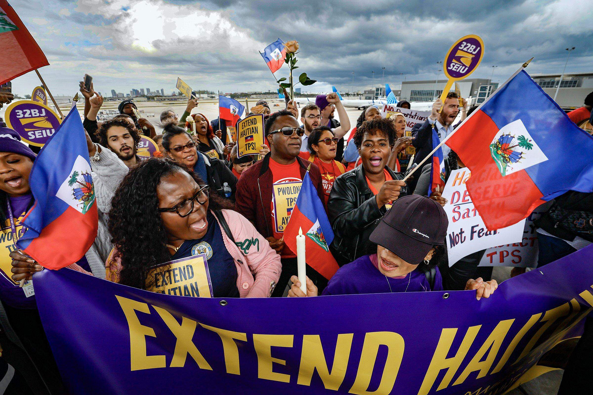 A crowd of protesters holds Haitian flags and signs calling for an extension of Haitian TPS.
